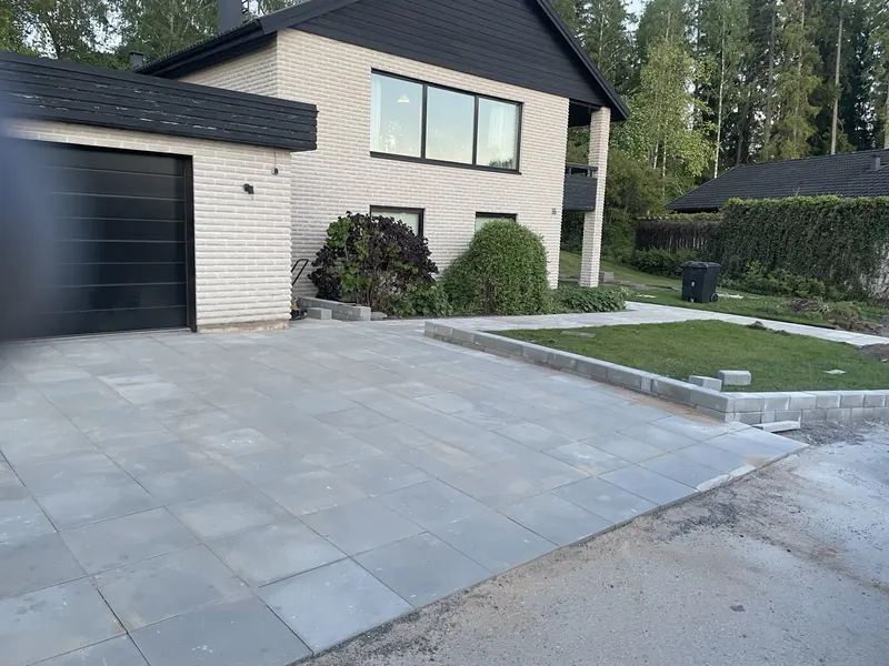 Ny stenläggning framför ett vitt hus